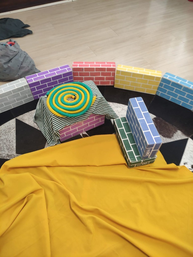 Espiral relacional com corda, pedestal de tijolos lúdicos e tecidos sobre o tapete